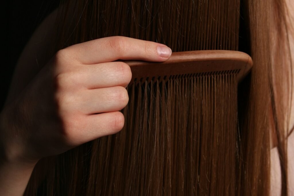 Photo by Mariia Horobets - KeratinXperts A hand combs long, brown hair.